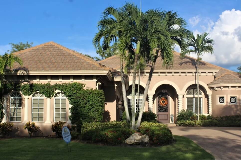 Shingle Roof on beige home in Southeast Florida. Home is surrounded by palm trees and bushes.